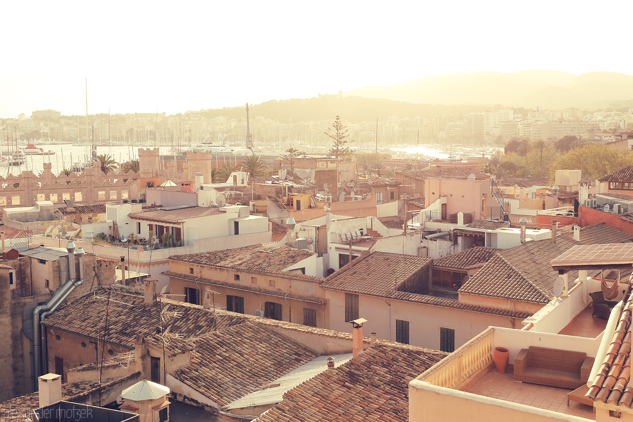 Foto von Soft sunrise over Palma, embracing terracotta rooftops with a warm golden hue against a tranquil seascape.