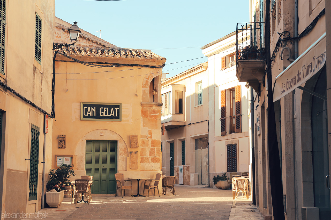 Foto von Sun-dappled facades and empty chairs in Santanyí's tranquil streets, capturing the serene spirit of Mallorca.