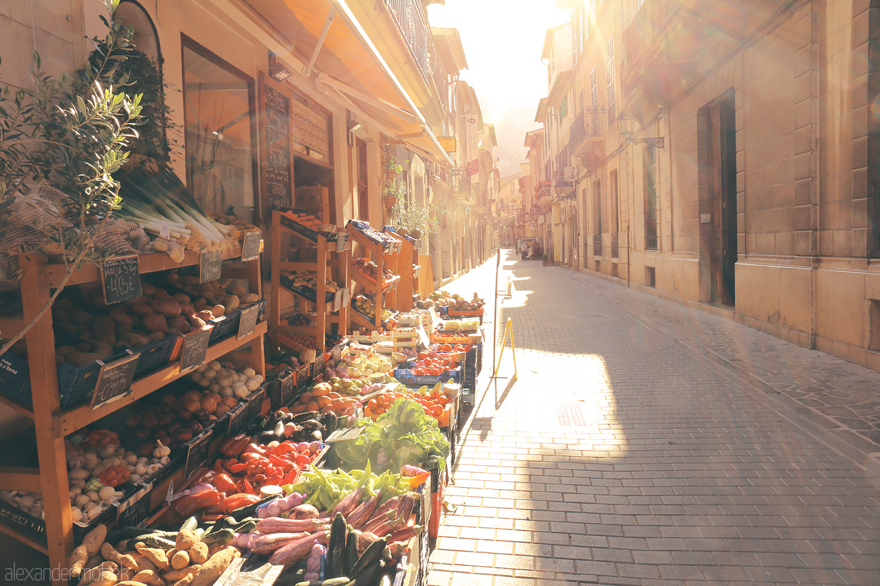 Foto von Warm sun rays cascade over Sóller's vibrant market street, capturing the essence of Mallorcan life.