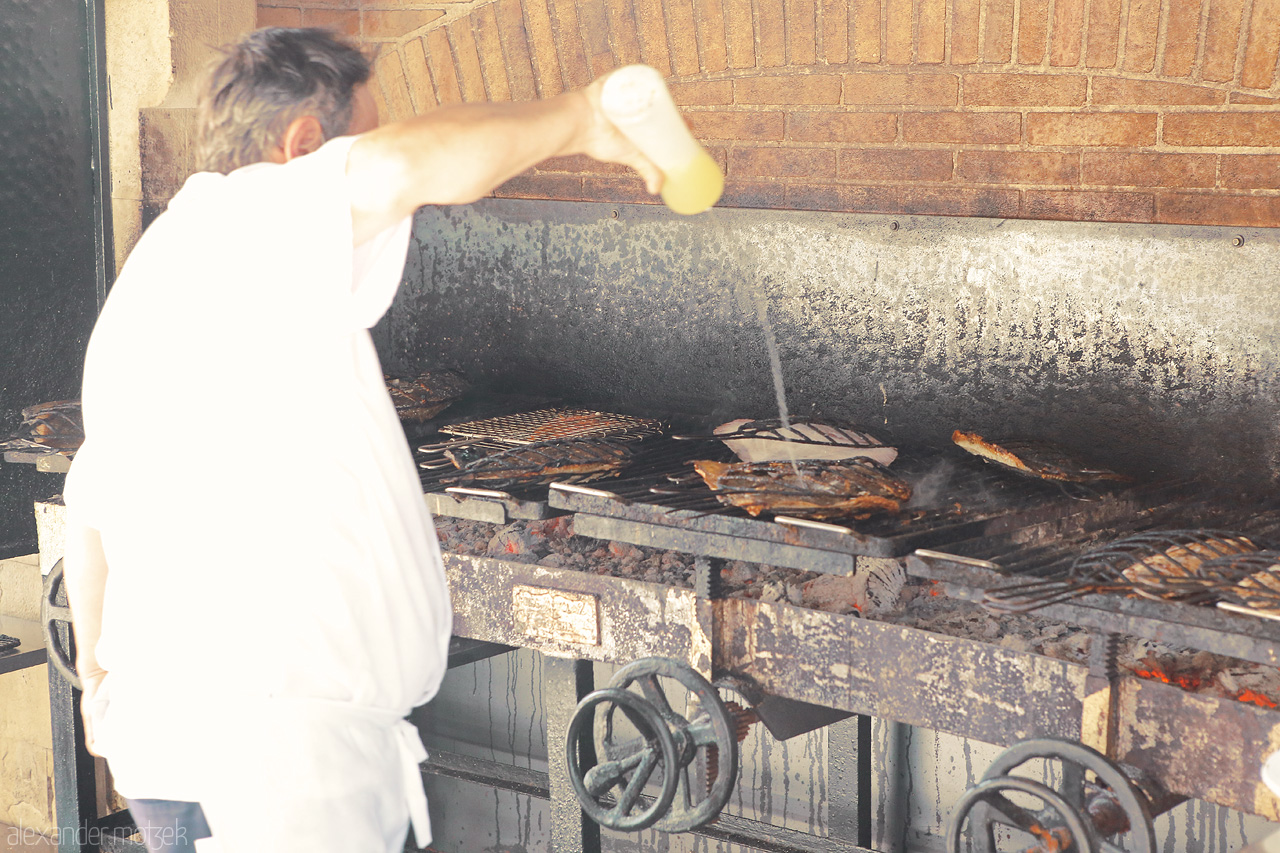 Foto von A chef in Getaria, Spain, masterfully grilling seafood over a traditional Basque-style barbecue.