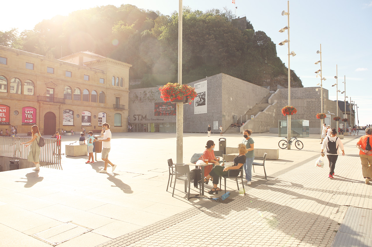 Foto von A serene San Sebastián plaza basks in golden sunlight, locals enjoying relaxed outdoor conversations.