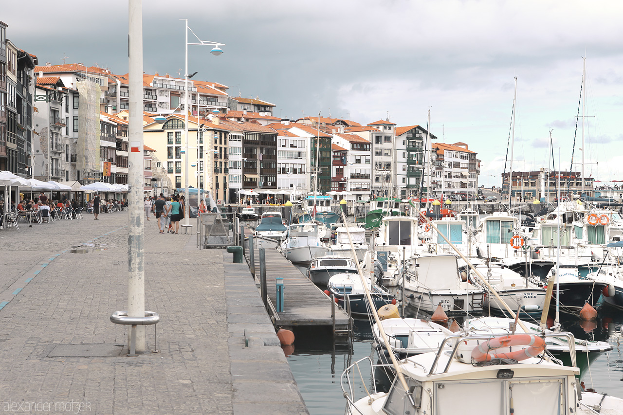 Foto von Lekeitio's lively harbor, with boats lined up and the Basque town's architecture in the background.