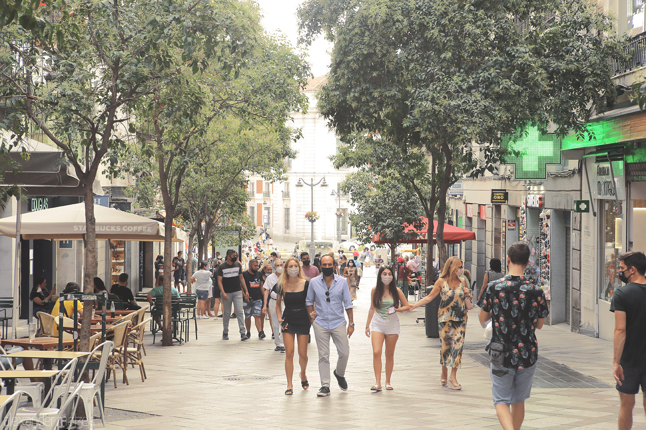 Foto von Lively street scene captures the essence of Madrid, with locals & tourists mingling under verdant trees.