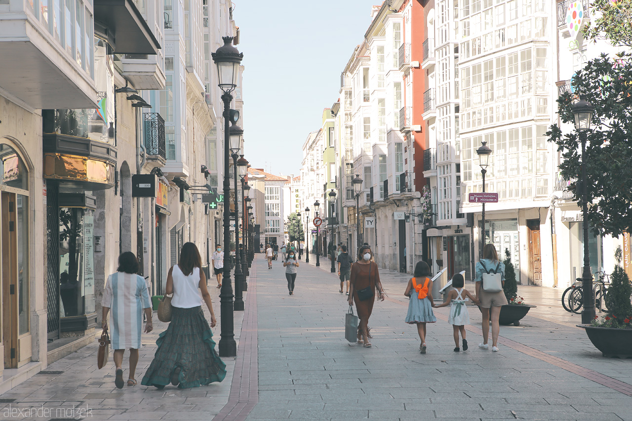 Foto von Strolling through a sunlit street lined with traditional Spanish architecture and local shoppers in Burgos.