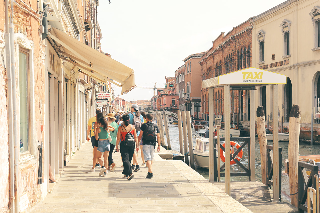 Foto von A serene stroll by Murano's sunlit canal, showcasing the beauty of Venetian life and vibrant architecture.