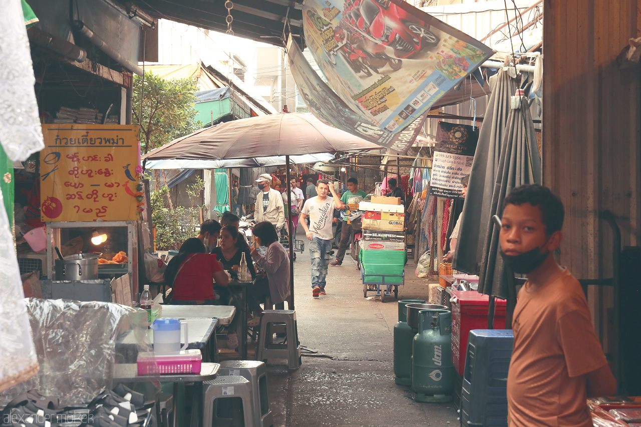Bangkok Breezes Foto von A bustling alleyway in Wang Burapha, Bangkok captures the vibrant essence of Thai street life with colorful signs and lively locals.
