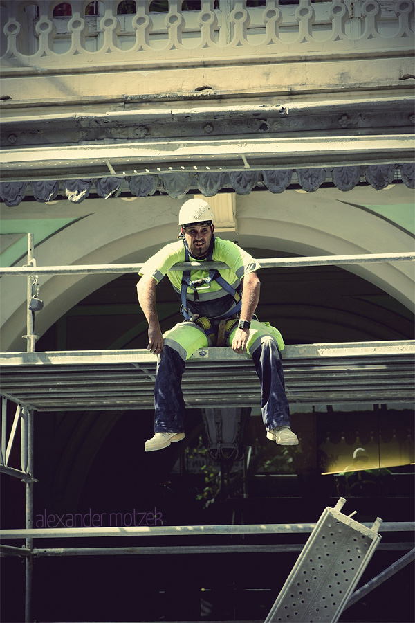 Gaudí's Guardians Foto von A construction worker rests on scaffolding with Barcelona's vibrant architecture in the backdrop, embodying the city's blend of old and new.