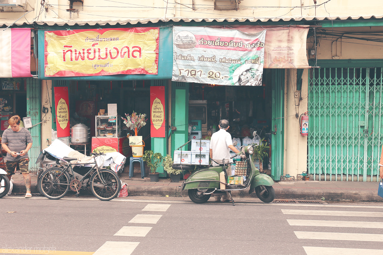 Bangkok Bazaar Whispers Foto von A lively scene in San Chao Pho Suea, Bangkok, showcasing vibrant street life, vintage scooters, and local shops full of character.