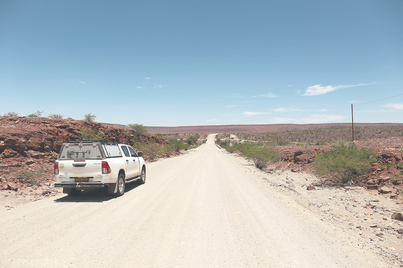 Namib's Endless Paths Foto von A lone vehicle traverses the gravel roads amidst Hardap's rugged terrain under the vast Namibian sky.