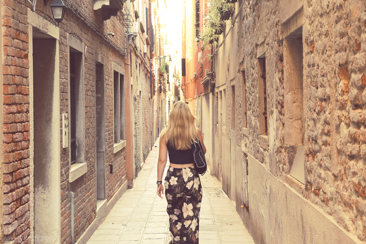 Calle Incantata Foto von A lone wanderer strolls down a narrow, sun-kissed alley in the heart of Venice.
