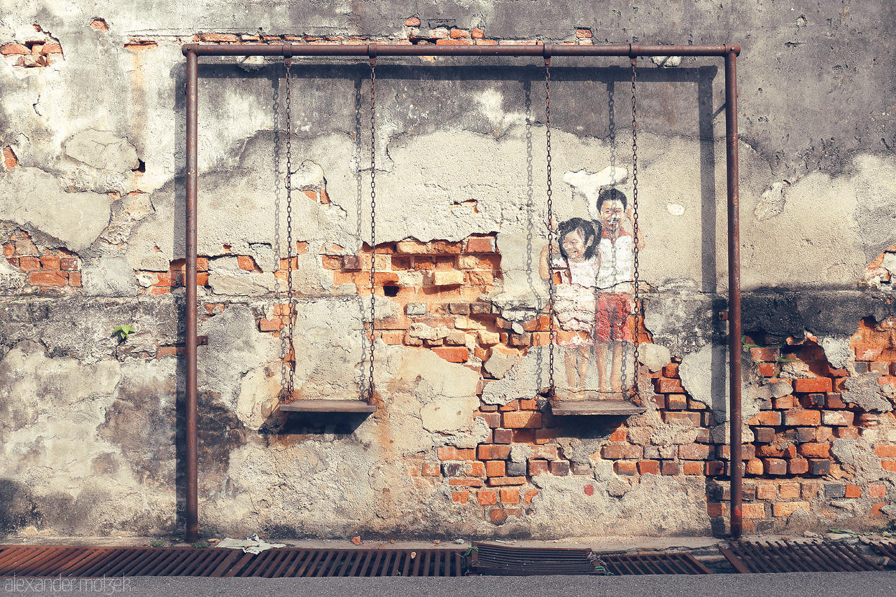 Swing Dreams Foto von A nostalgic mural with swings on a weathered wall in Penang captures the essence of childhood and heritage.