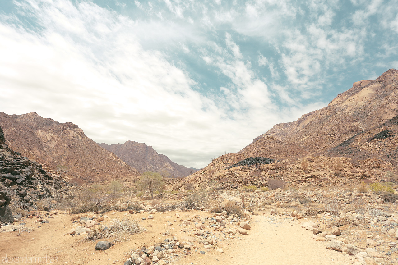 Damaraland's Silent Charm Foto von A serene trail through Brandberg's arid landscape under a vast sky in Namibia.
