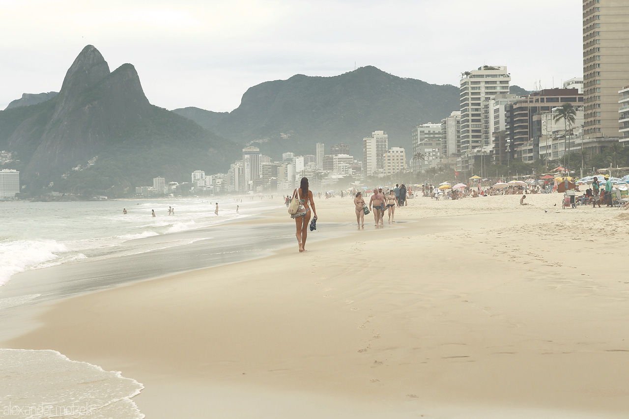 Beleza de Ipanema Foto von A serene walk along Ipanema Beach, Rio de Janeiro, with the Dois Irmãos hills majestically overlooking the bustling cityscape