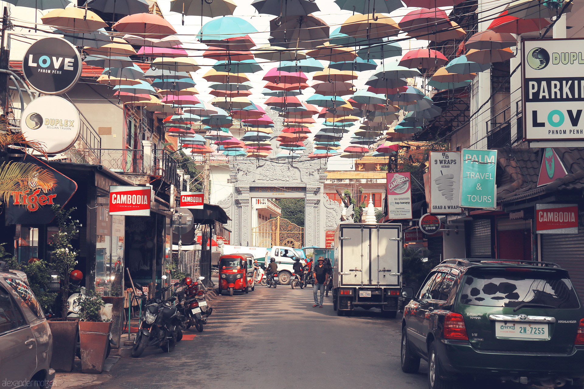 Champey Shadows Foto von Colorful umbrellas float above a lively Phnom Penh street, blending Khmer spirit with urban bustle beneath the tropical sky.