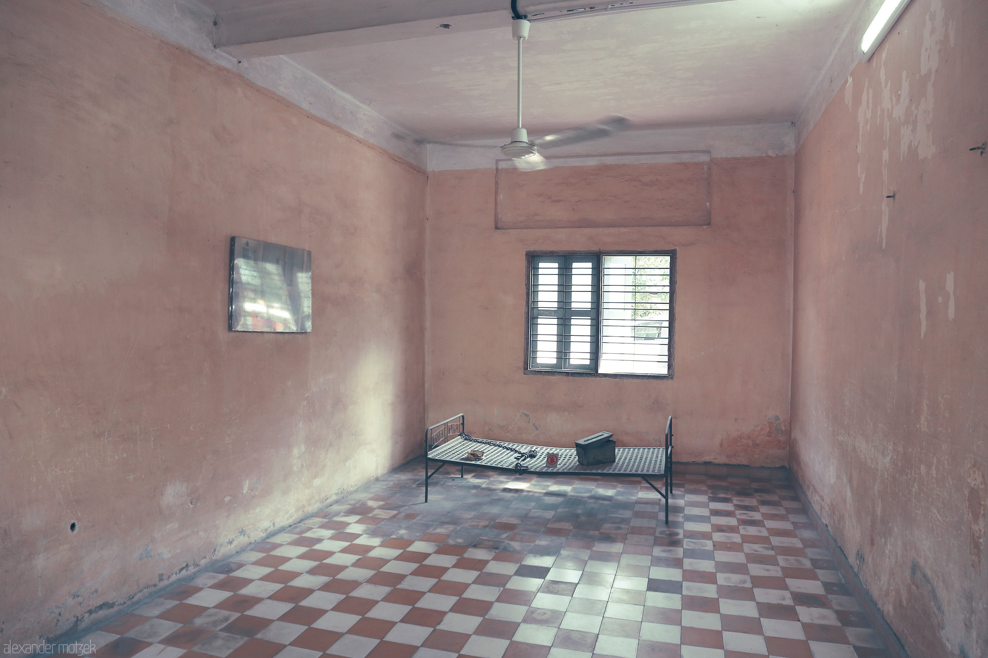Sorrow of S-21 Foto von Empty cell in Tuol Sleng Genocide Museum, Phnom Penh. Stark bed, barred window, and muted walls bear witness to Cambodia's haunting history.