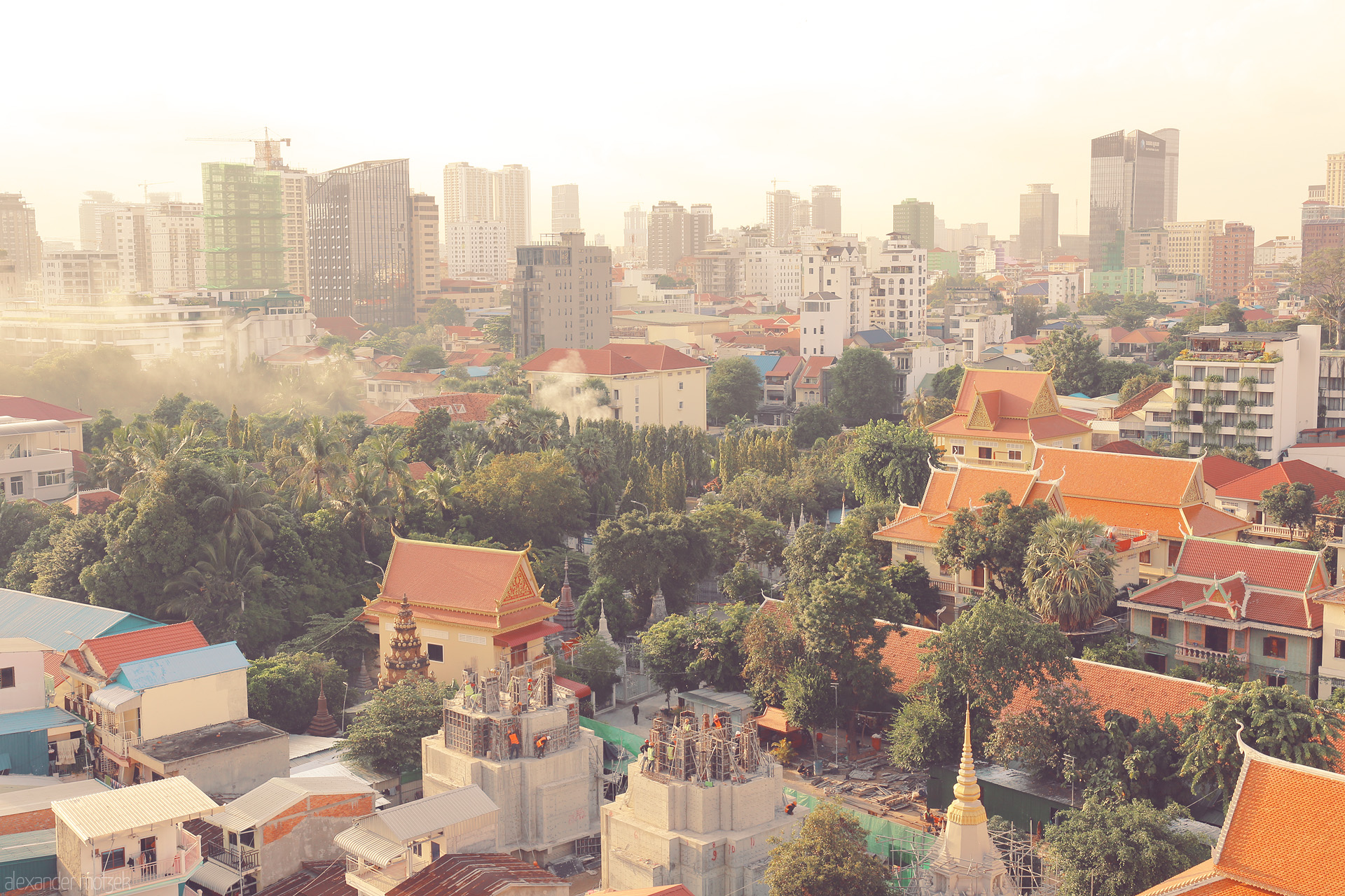Chaktomuk Reverie Foto von Golden dawn bathes Phnom Penh's red-roofed pagodas and rising skyline in a tranquil blend of tradition and modernity.