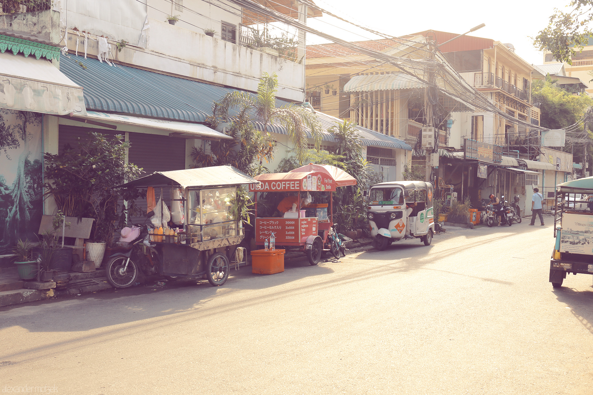 Kandal Kompong Mornings Foto von Golden morning light falls on street vendors and tuk-tuks in Kandal, Cambodia—a tranquil slice of daily life and coffee culture.