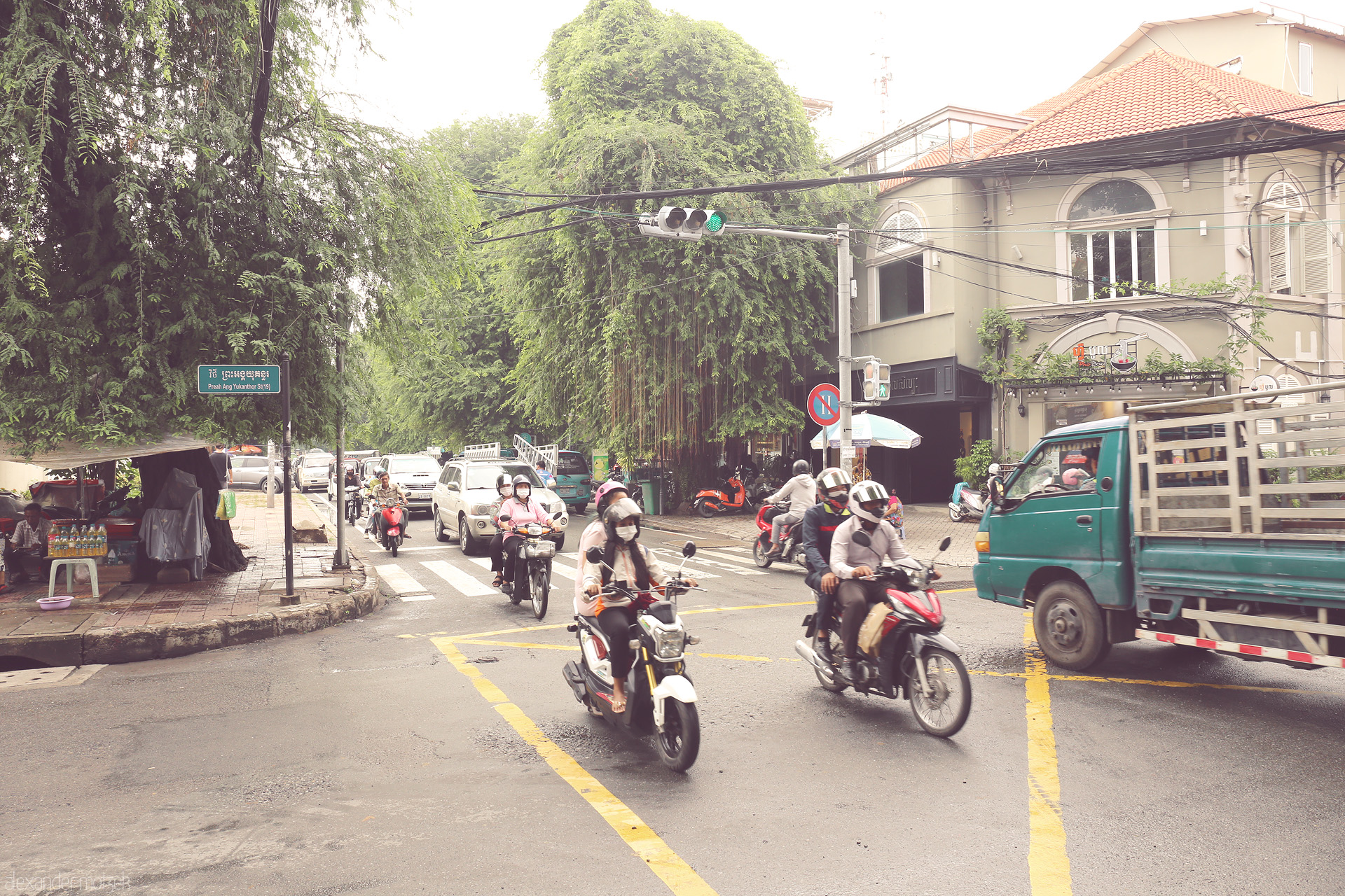 Kampuchea Krossroads Foto von Morning buzz at Preah Ang Yukanthor St, Phnom Penh — scooters, street eats, and lush greenery in a uniquely Cambodian dance.