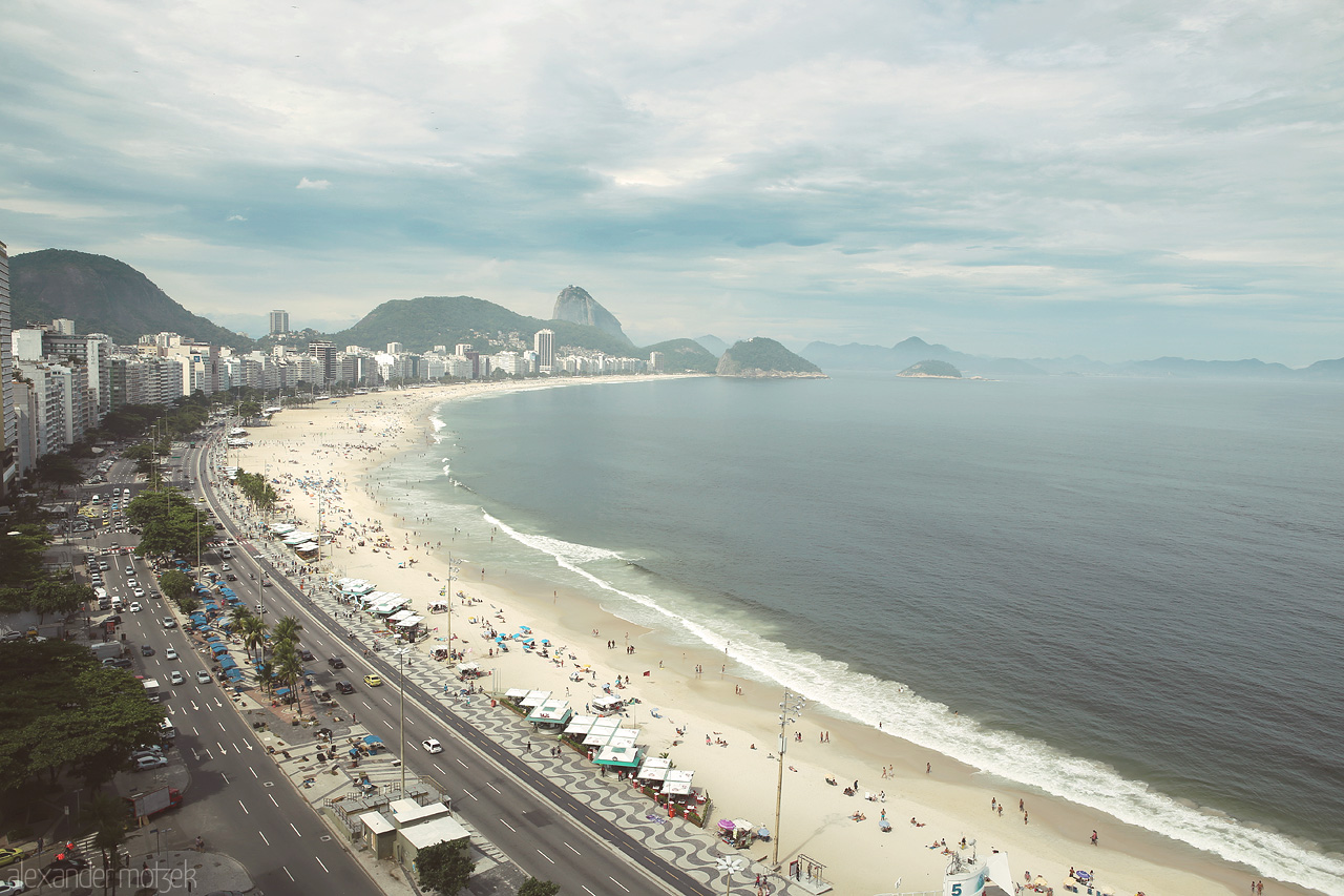 Cores de Copacabana Foto von Copacabana Beach stretches beneath a cloudy sky in Rio de Janeiro, where urban life meets pristine sands and ocean waves.