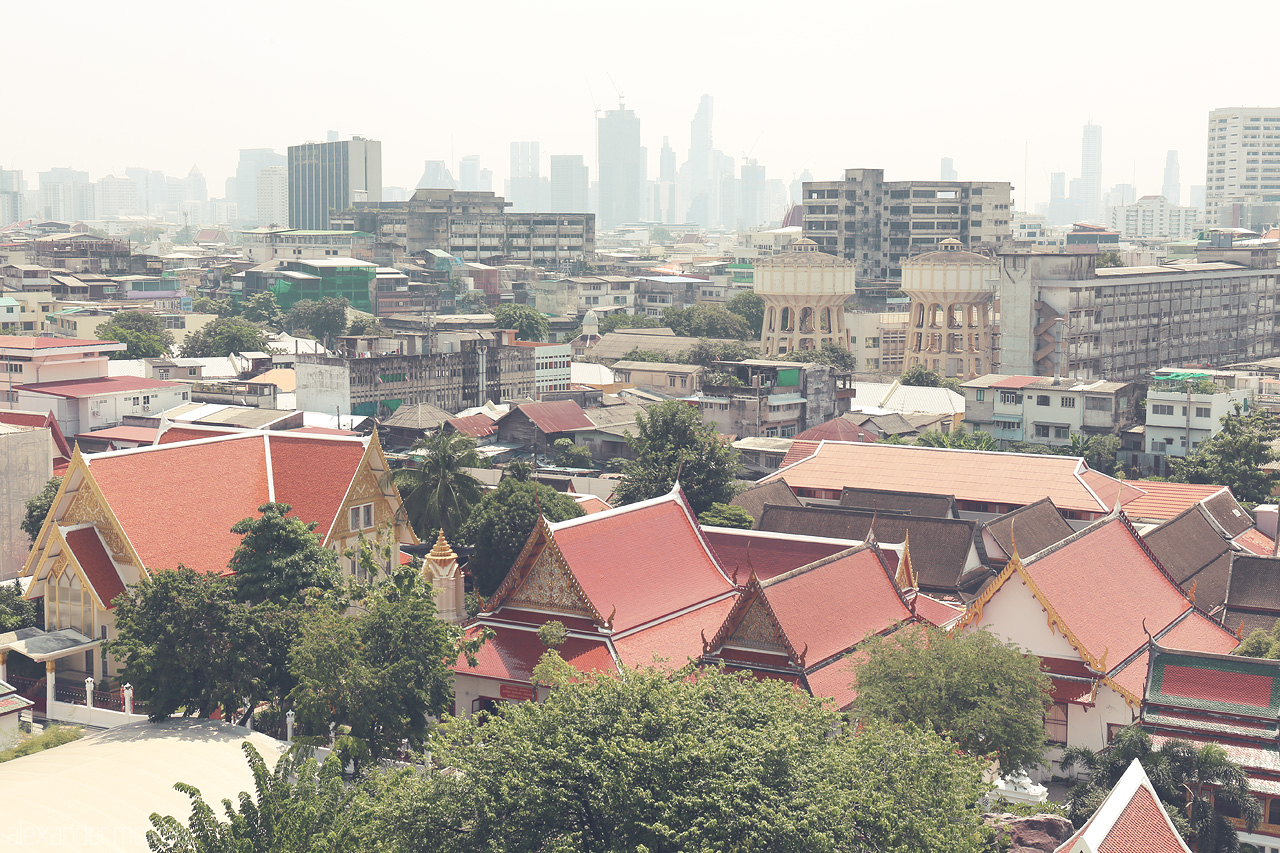 Saffron Serenity Foto von Historic rooftops of Ban Bat, Bangkok, with vibrant temples against a backdrop of modern skyscrapers, blending tradition with urban life.