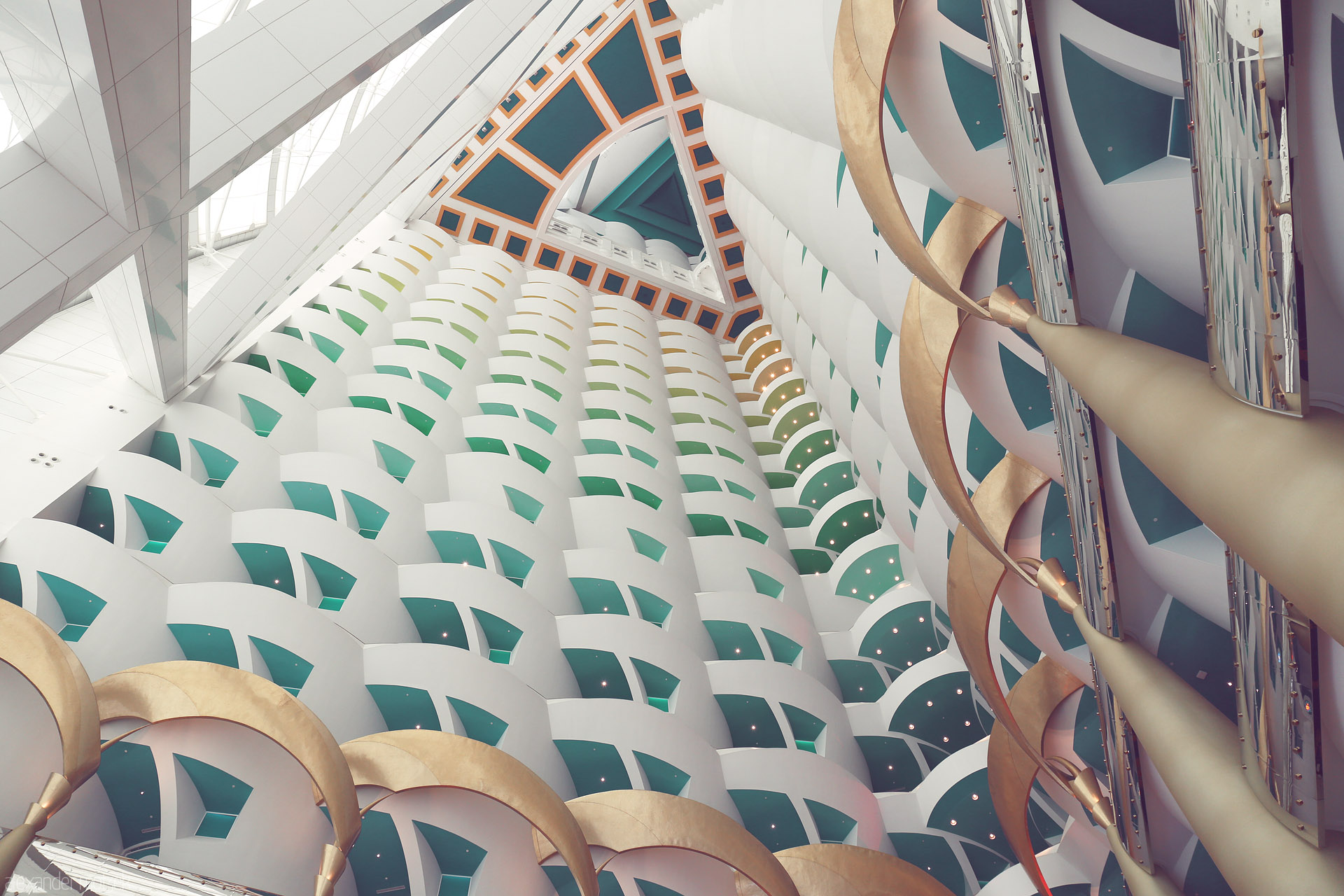 Arabesque Vertigo Foto von Inside Dubai’s Burj Al Arab: soaring geometric patterns, golden arches, and turquoise hues capture the city’s opulent modernity.
