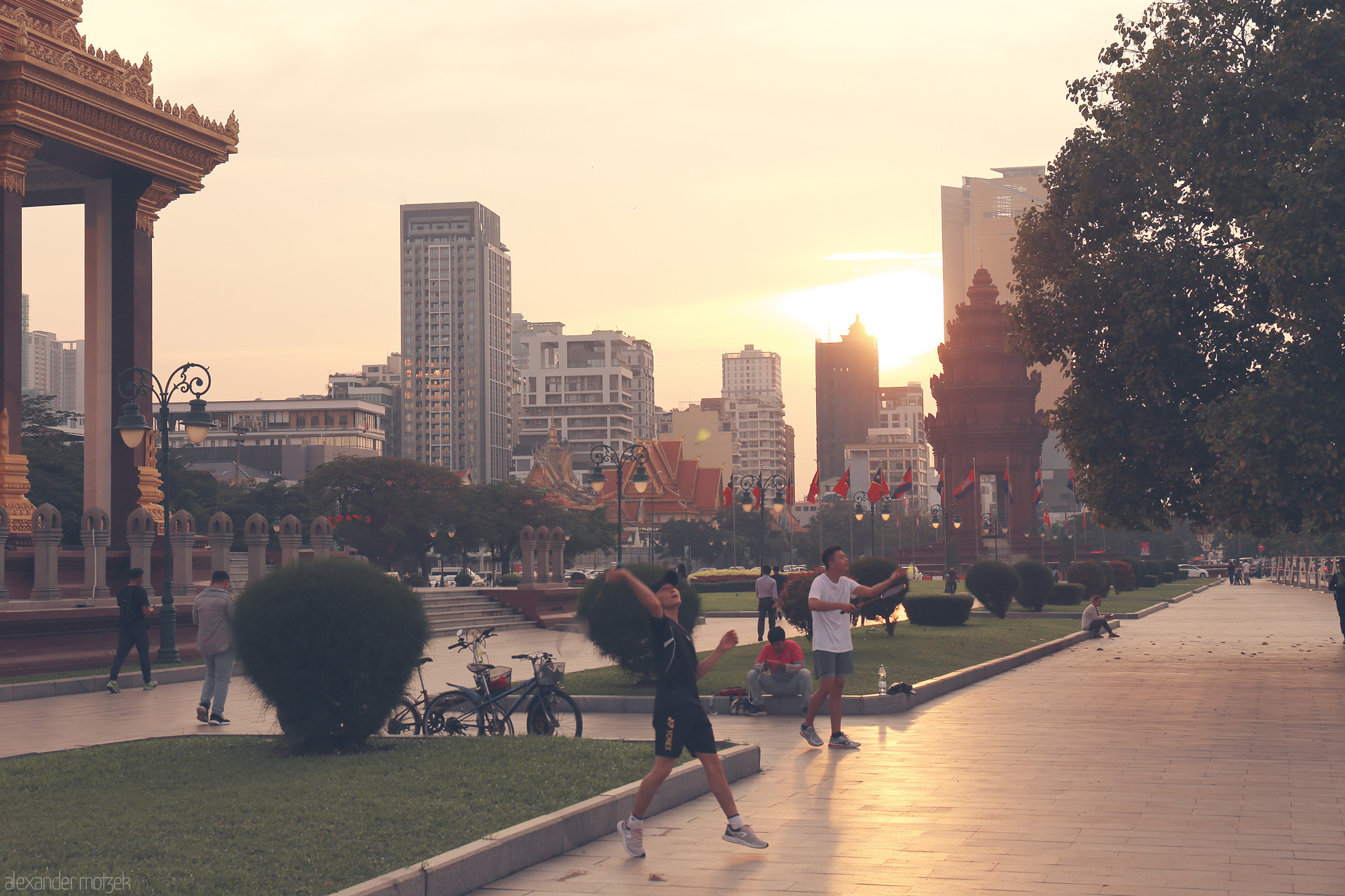Foto von Locals play at dusk near the Independence Monument, Phnom Penh, blending Khmer heritage with modern city life beneath a golden sky.
