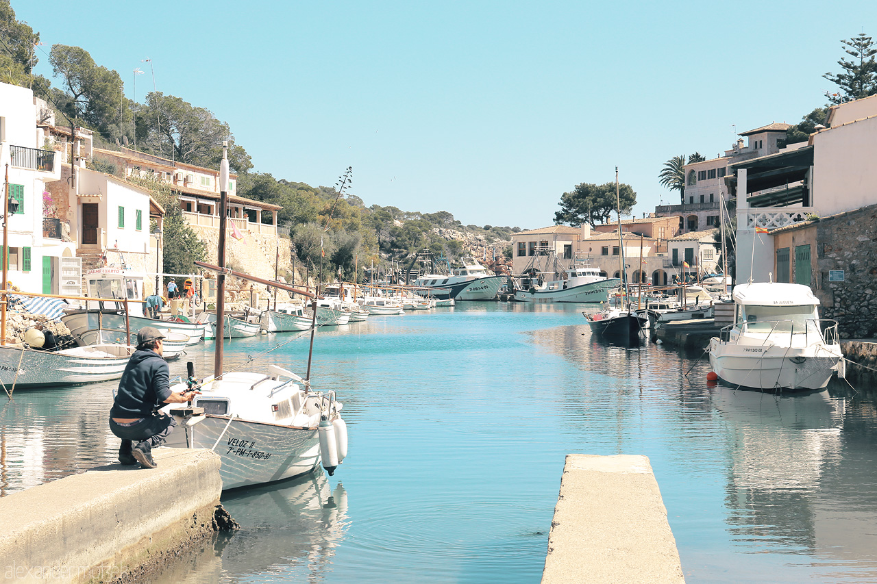 Mallorca's Azure Cala Foto von Tranquil boats afloat in Cala Figuera's clear waters, traditional architecture lining the serene Mallorcan coast.