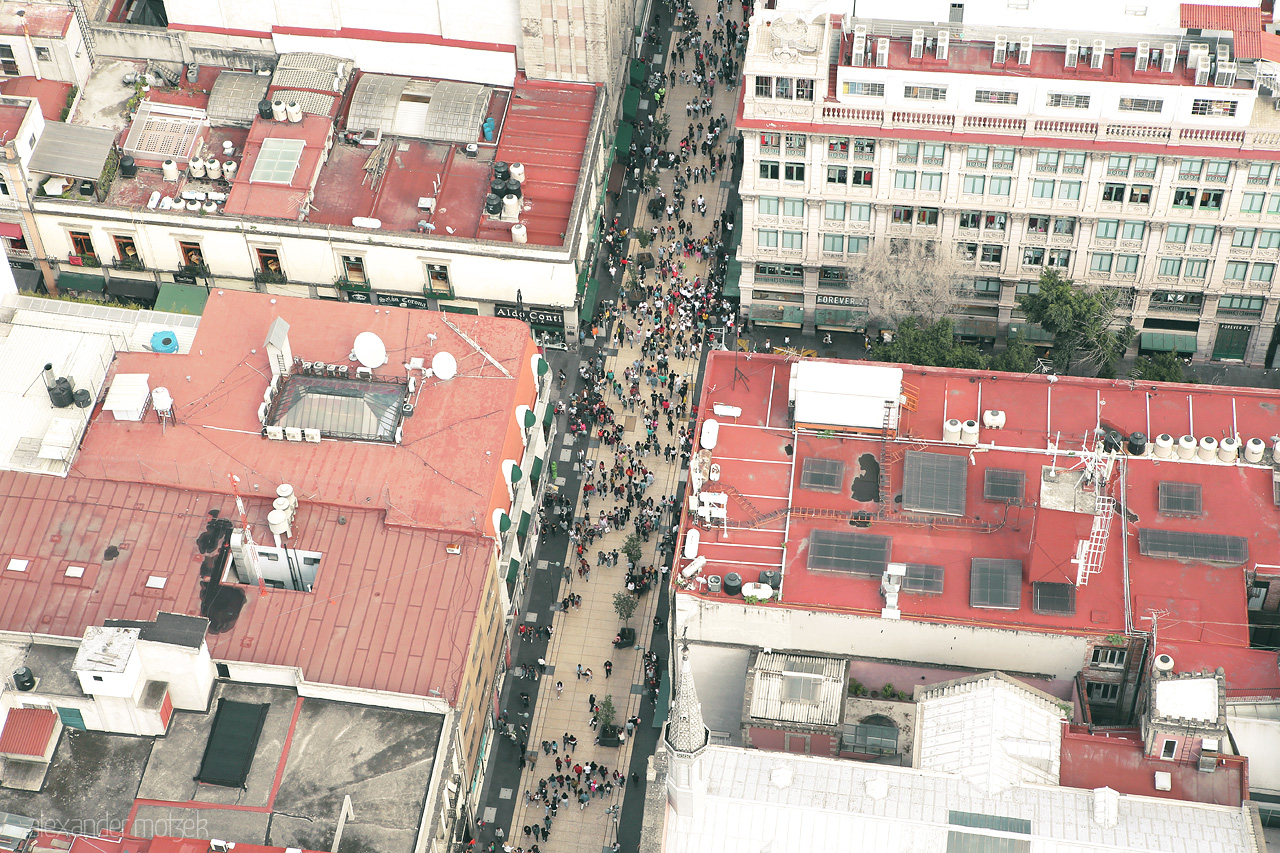 Foto von A bird's-eye view of bustling CDMX, with people dotting the streets between architectural reds.