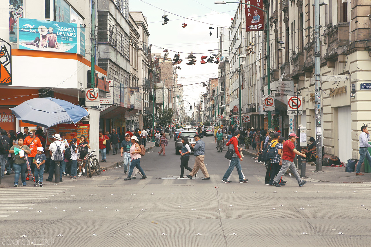 Foto von Pedestrians cross a bustling street in Cuauhtémoc, with shoes overhead hinting at local urban tales.