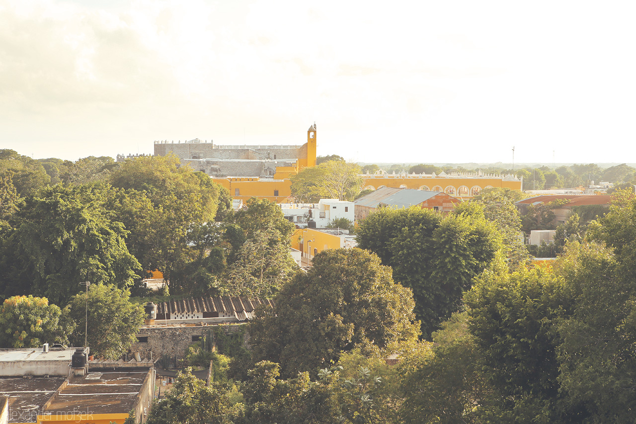 Foto von Sunlit treetops fronting Izamal's iconic yellow architecture, a serene dawn in Yucatán.