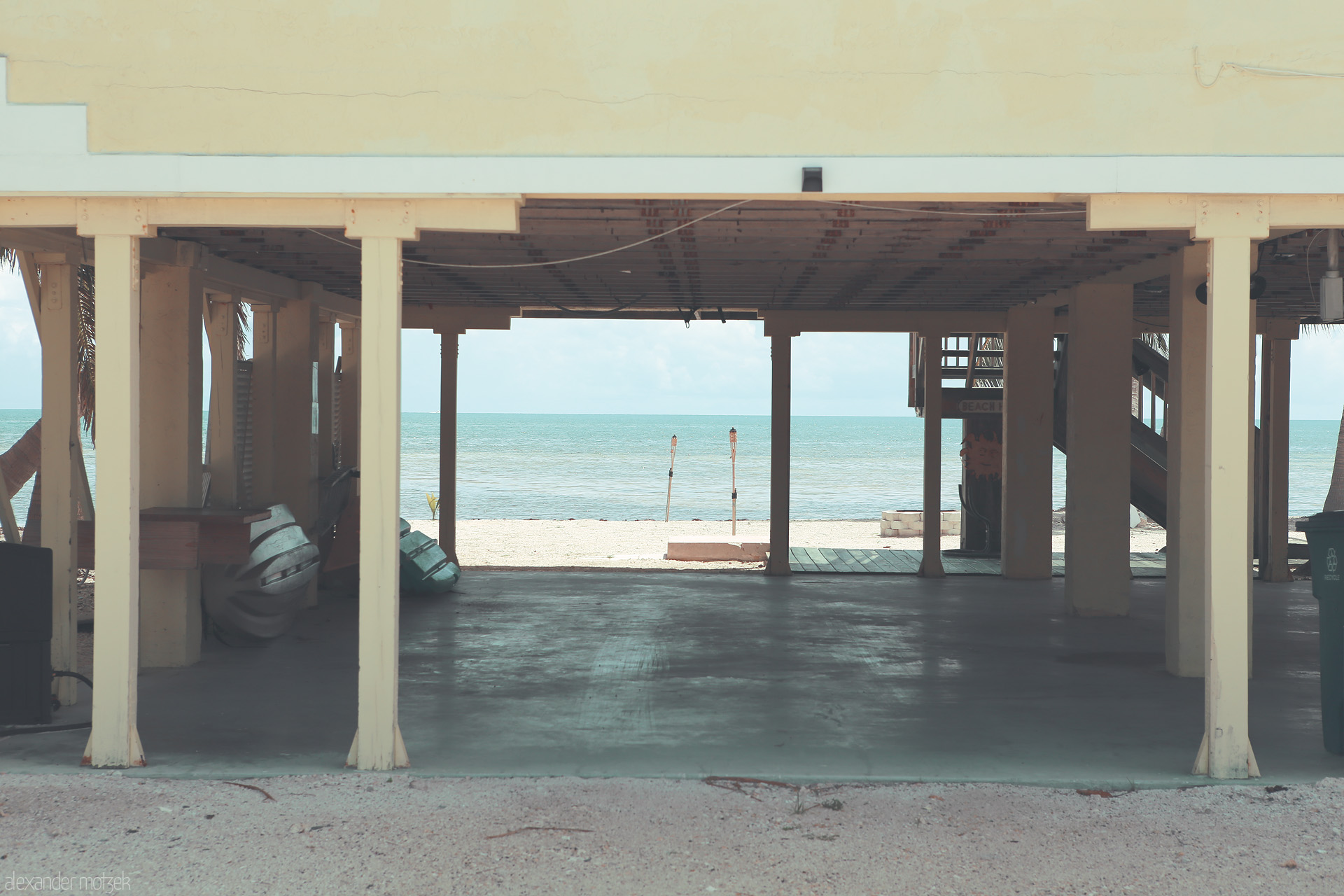 Ocean’s Embrace Foto von Sunlit beach shack in Monroe County with open view of the serene ocean through rustic pillars.