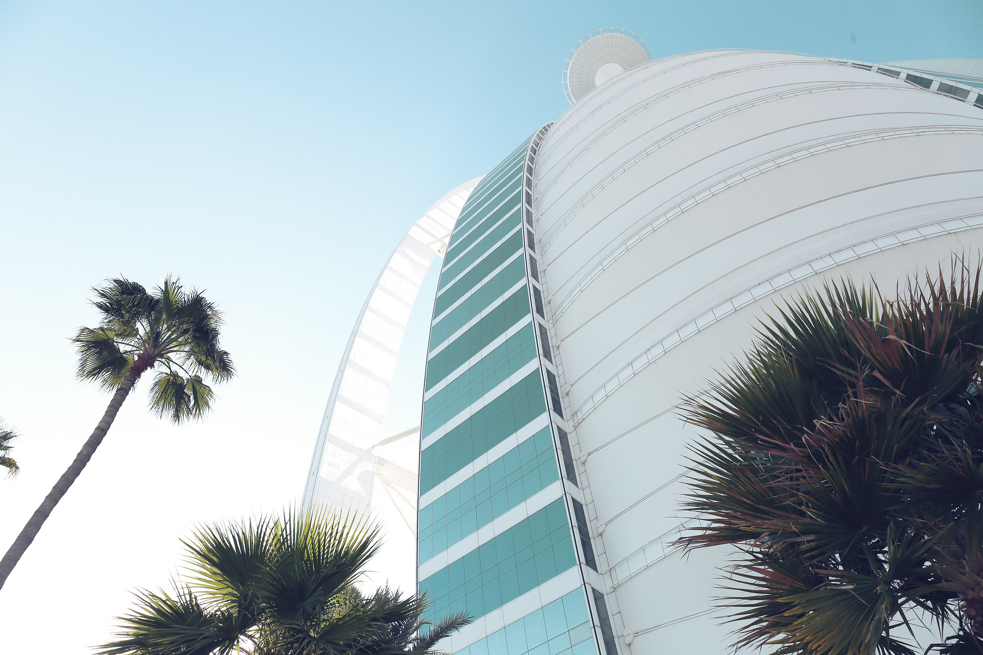 Jumeirah Dreams Foto von Palm trees sway beneath the iconic sail-shaped Burj Al Arab, basking in the Dubai sun—a fusion of luxury and desert ambition.