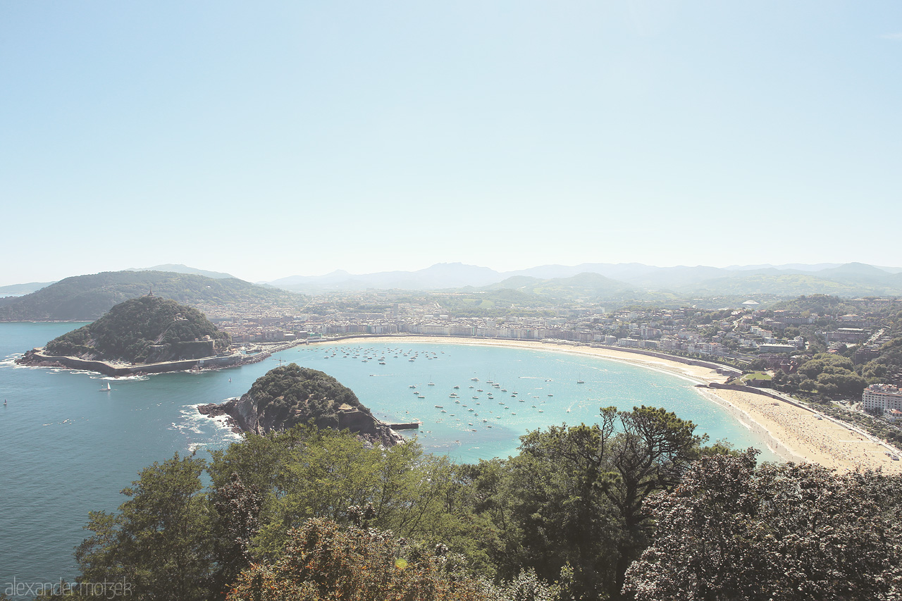 Donostia Horizons Foto von Panoramic view of San Sebastián's sweeping bay, La Concha Beach, embraced by verdant hills under a clear azure sky.