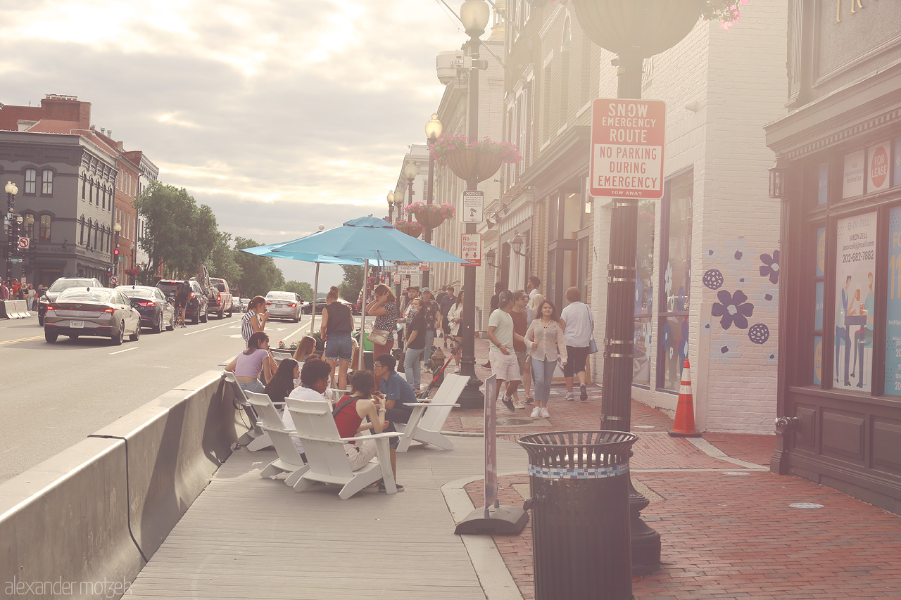 Chill in Georgetown Foto von Relaxed summer vibes in Georgetown, D.C. capture locals lounging on a bustling street with vibrant shops and charming city atmosphere.
