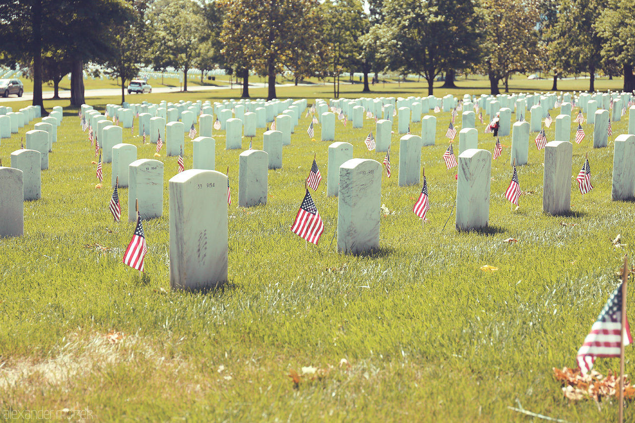 Echoes of Valor Foto von Rows of gravestones with American flags at Arlington National Cemetery, reflecting a solemn tribute.