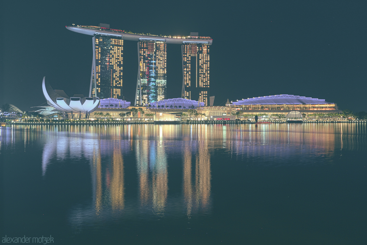 Marina Bay Nocturne Foto von A mesmerising night view of Marina Bay Sands and surrounding architecture in Singapore, beautifully mirrored in the calm waters.