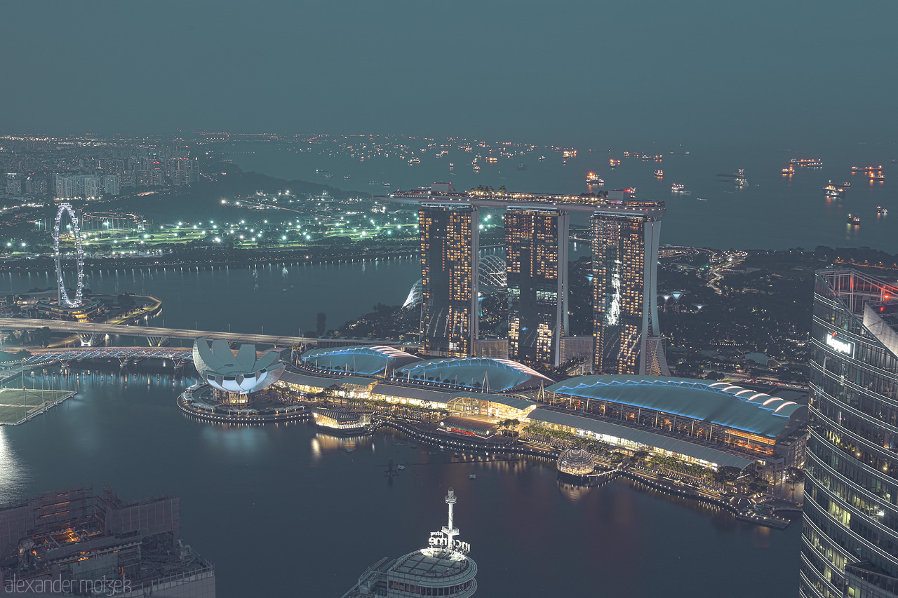 Lion City's Lumiere Foto von A panoramic view of Singapore's iconic Marina Bay Sands and Flyer, glowing against the twilight skyline and bustling bay.