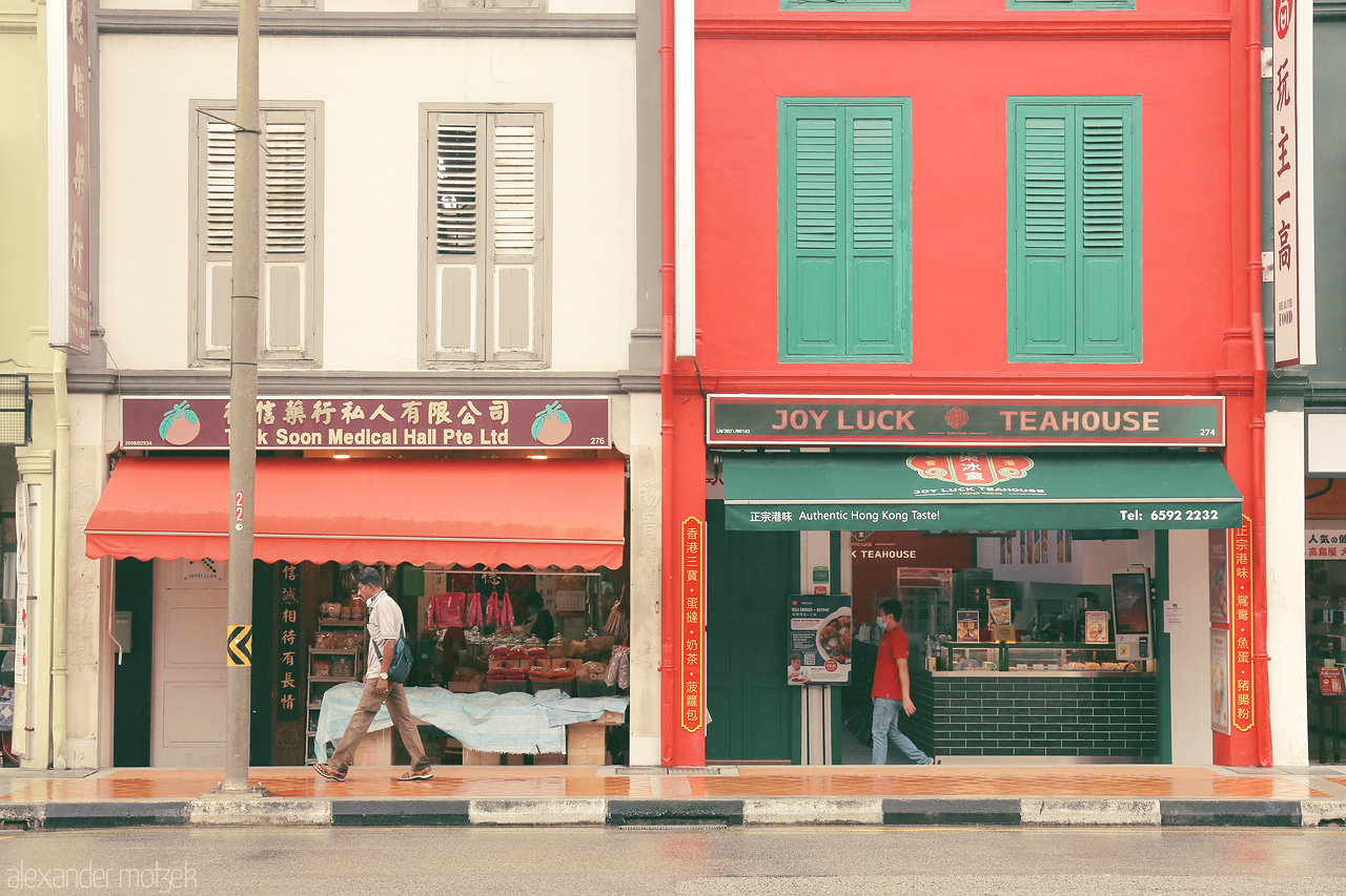 Colorful Kampong Serenity Foto von Exploring Singapore's Kampong Glam: a colorful shophouse street with a mix of medical shops and a cozy tea house. A journey of vibrant culture.