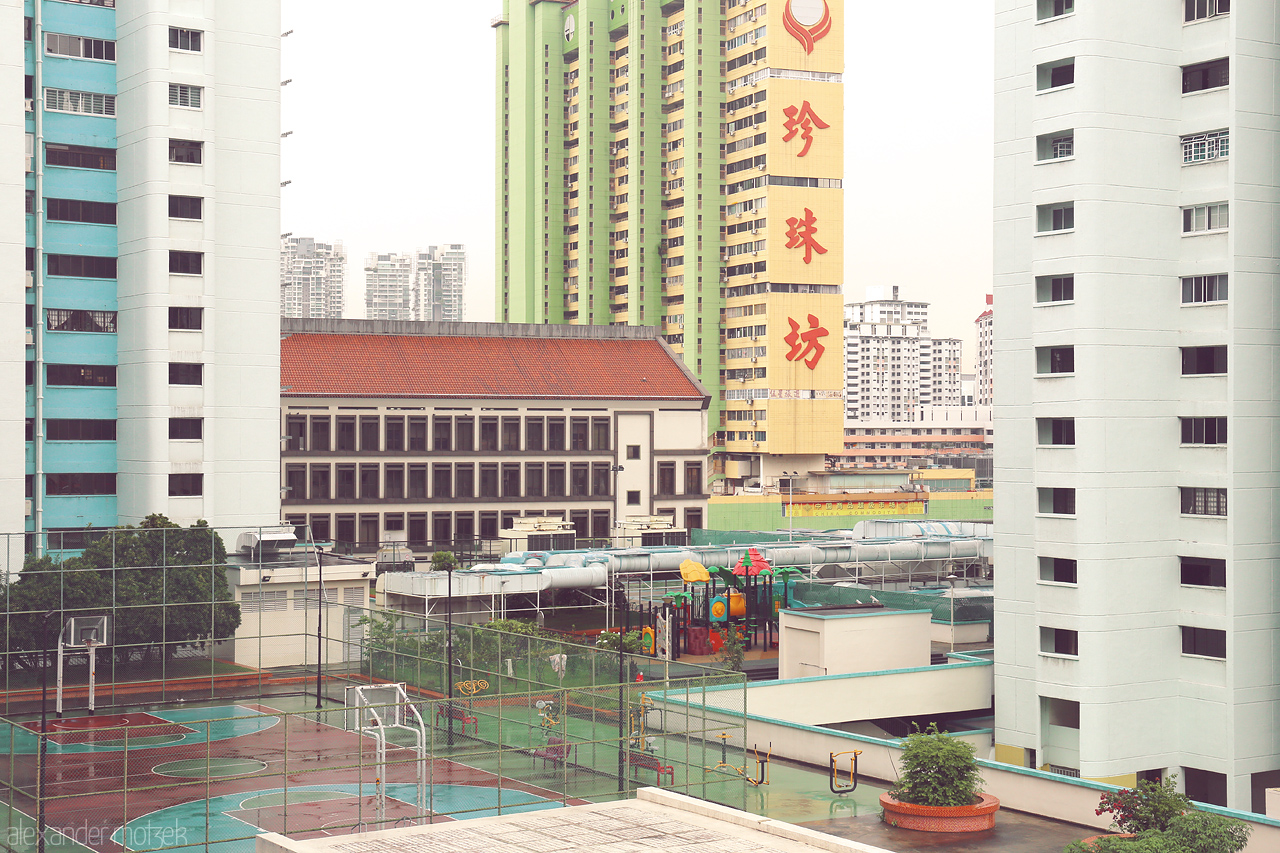 High-Rise Heartbeat Foto von Singapore's cityscape blending high-rise buildings with a serene basketball court and playground within Chinatown district.