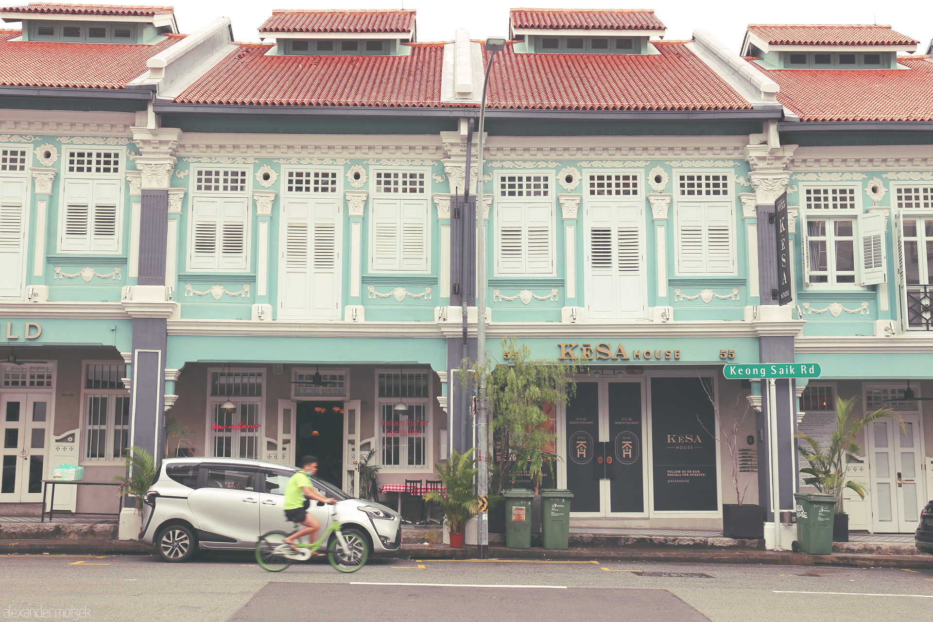 Peranakan Pulse, Keong Saik Foto von Turquoise Peranakan shophouses and a cyclist blend heritage and movement on historic Keong Saik Road, Singapore.
