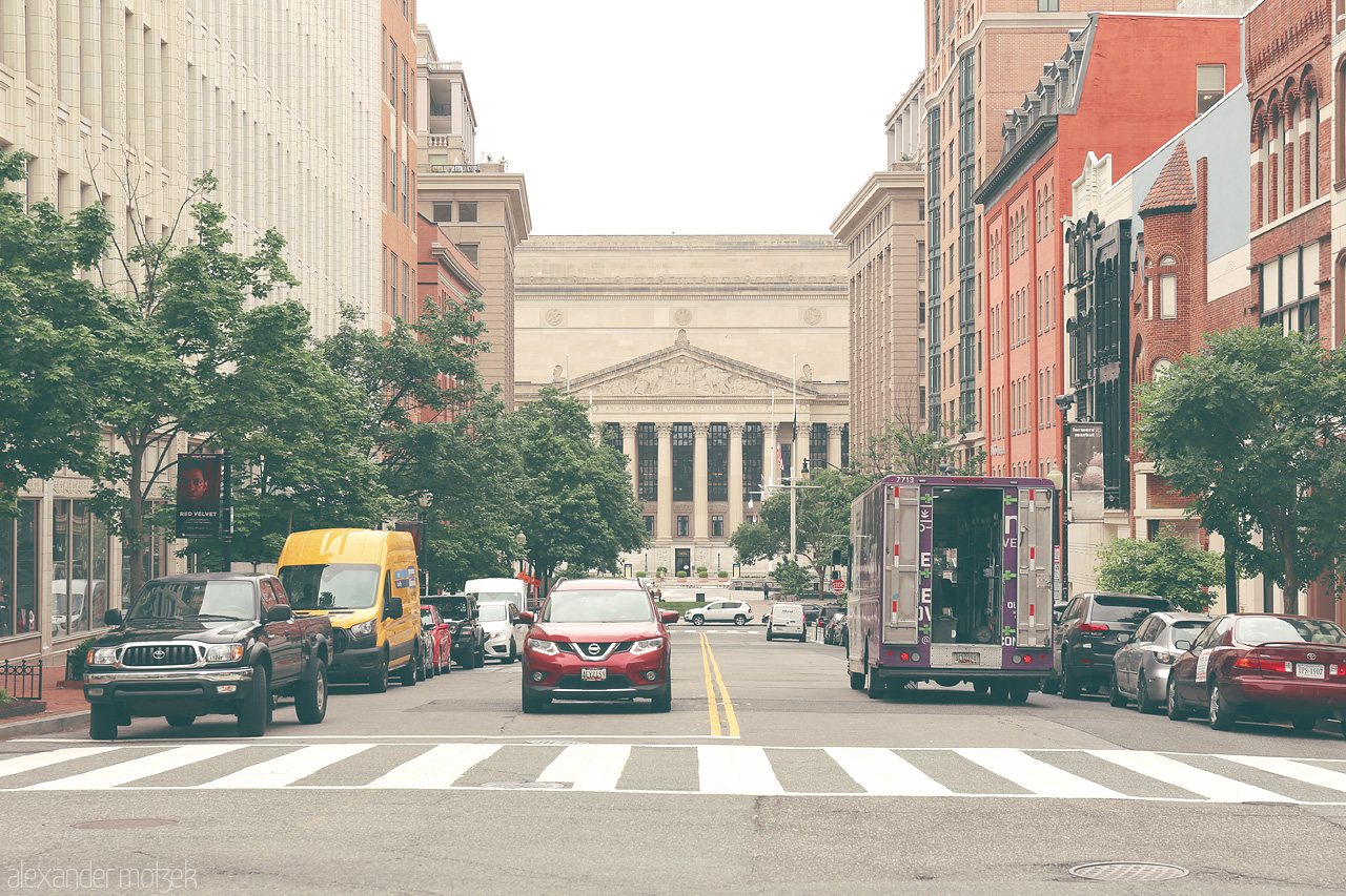 Capital Convergence Foto von Street scene in Washington, D.C., capturing the blend of modern vehicles and historic architecture with a stately building in the background.