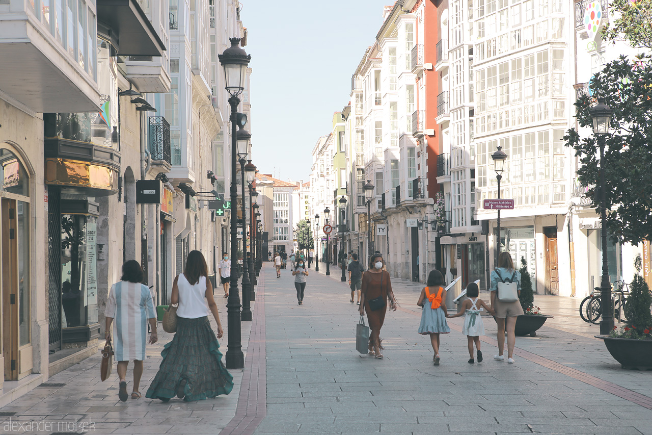 Burgos Paseo Callejero Foto von Strolling through a sunlit street lined with traditional Spanish architecture and local shoppers in Burgos.