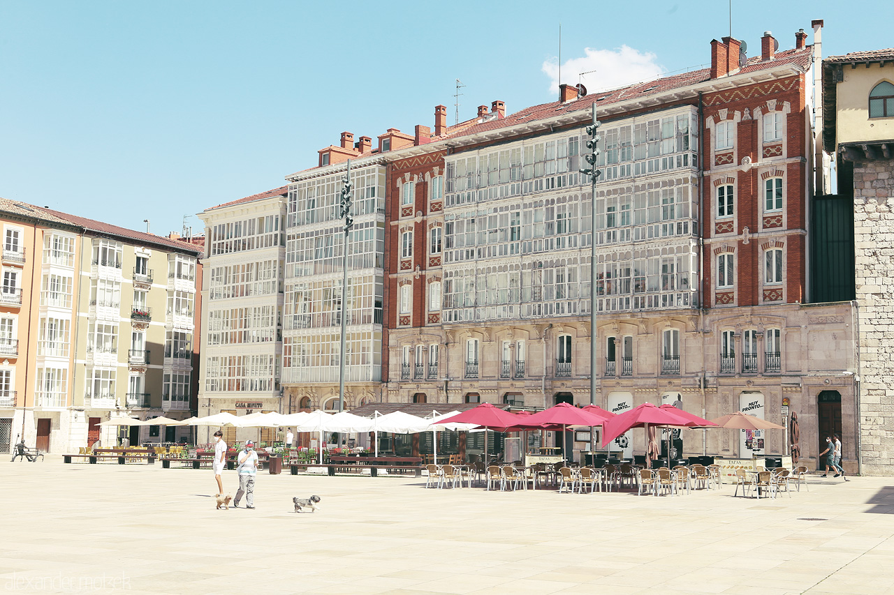 Burgos en Calma Foto von Sun-drenched plaza in Burgos, Spain, flanked by historic buildings and lively terraces.