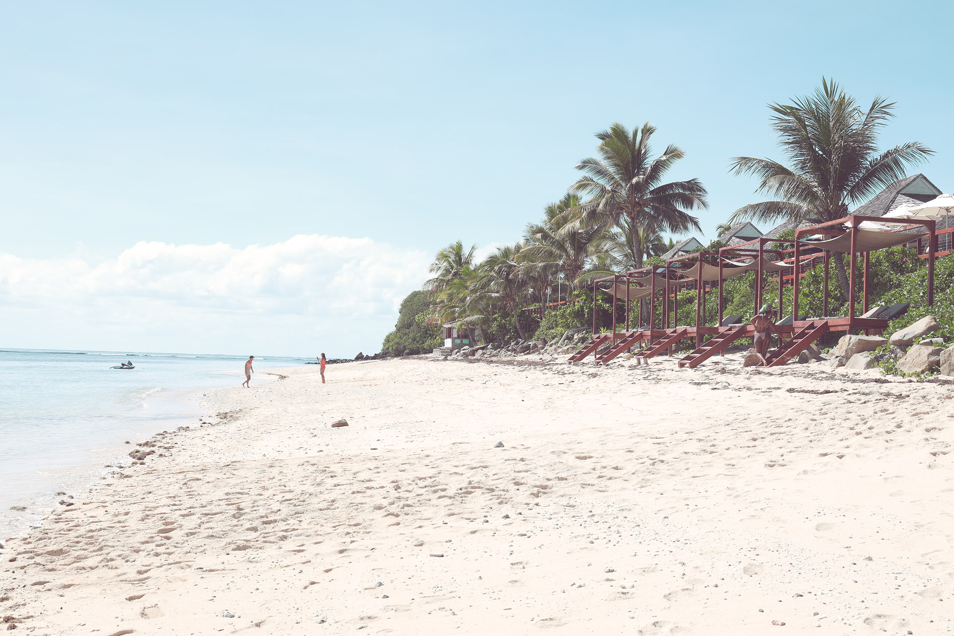Foto von Sunlit Tokoriki, Fiji beach with calm lagoon, pale sand, palms, and resort loungers under shade sails.