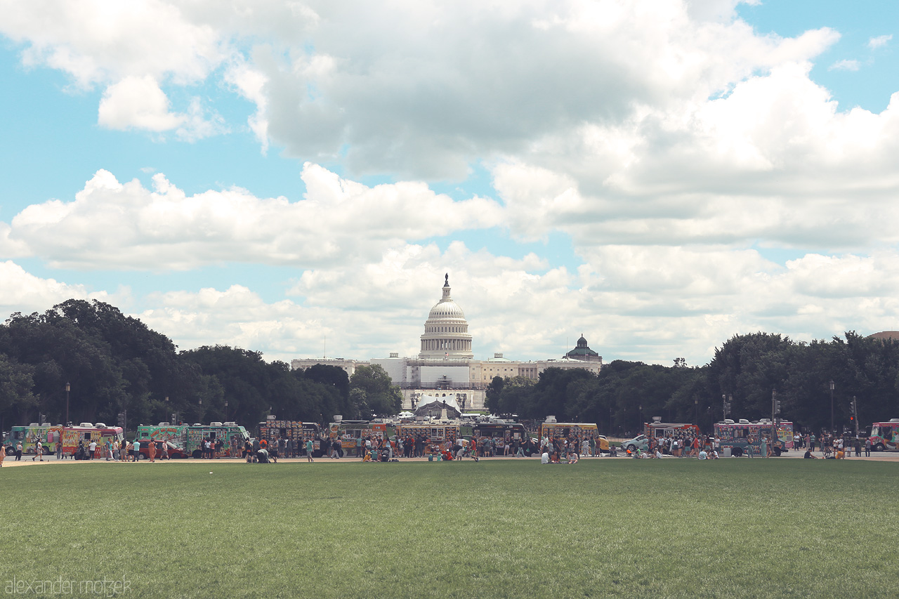Capitol Soliloquy Foto von The U.S. Capitol stands majestically under a wide sky, framed by the lush National Mall and flanked by vibrant stalls in Washington, D.C.