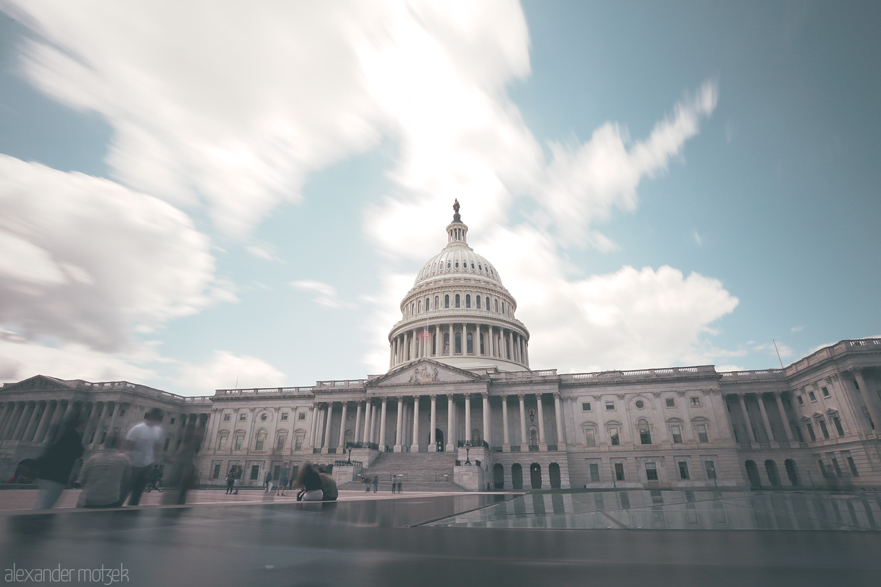 Capitol Serenity Foto von The iconic dome of the U.S. Capitol in Washington D.C. under a daylit sky, capturing its timeless grandeur and bustling foreground.