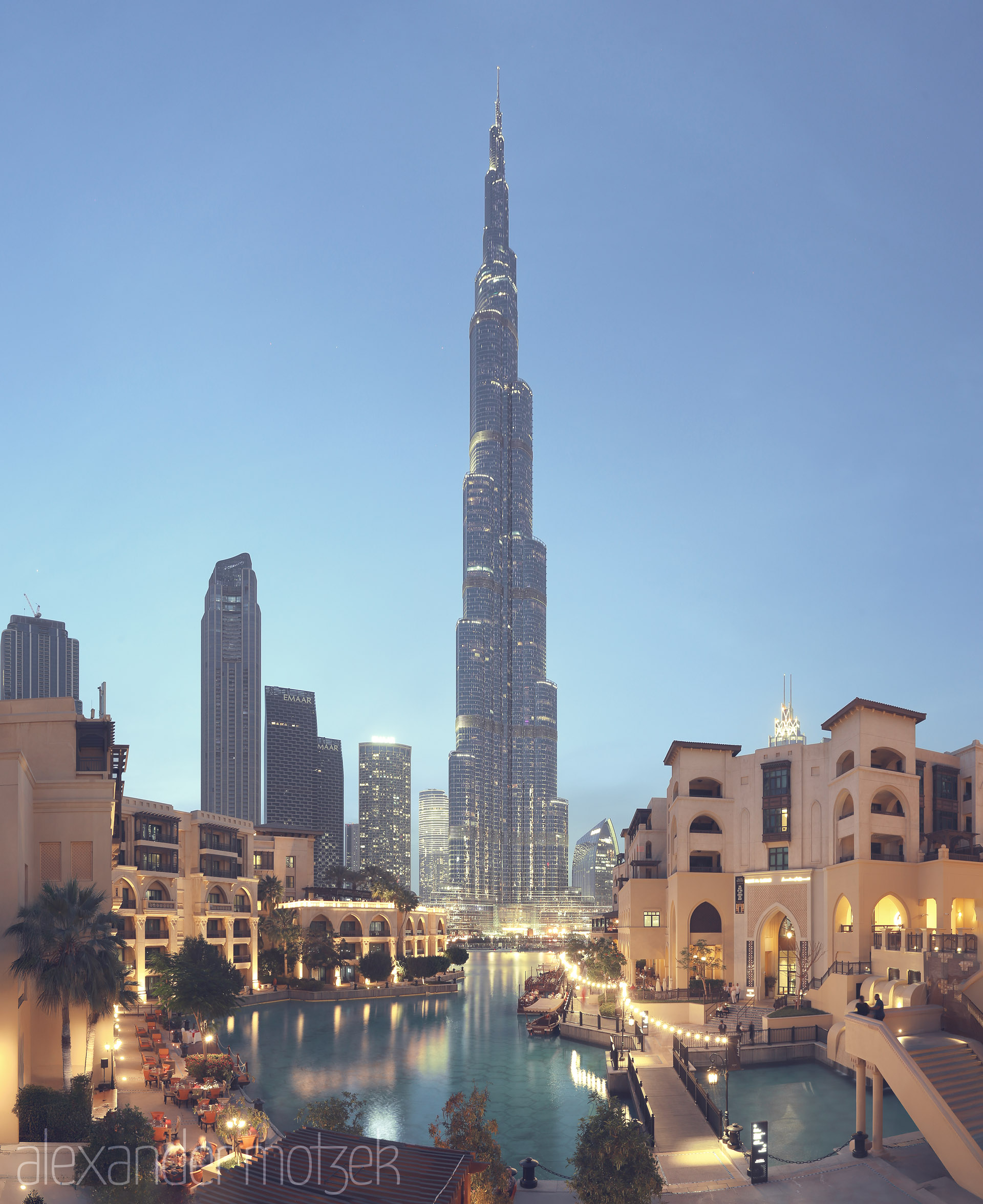 Noor Over Burj Foto von Twilight at Burj Khalifa rises beyond tranquil waters and glowing souks, capturing Dubai’s modern heartbeat and timeless charm.