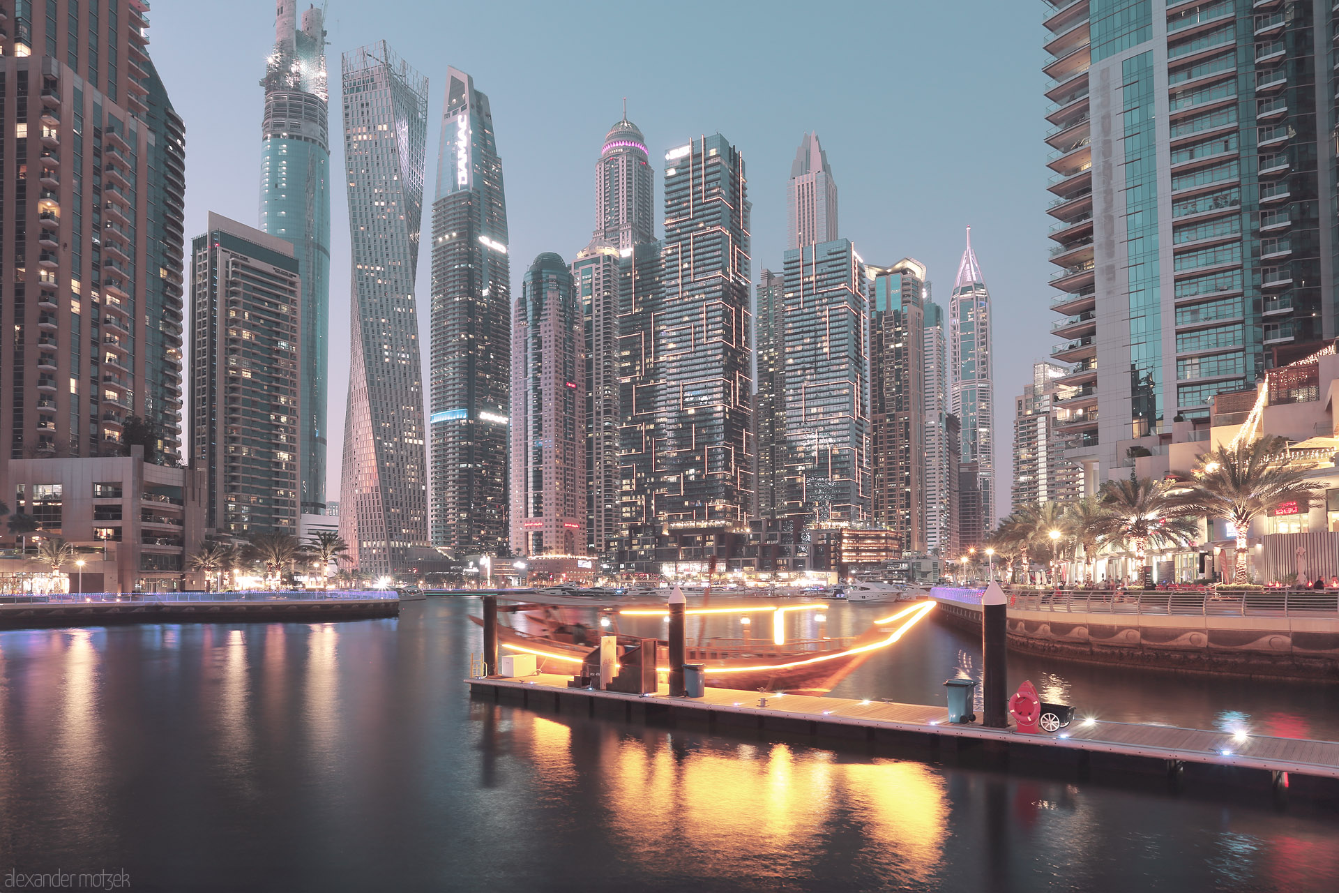 Foto von Dubai Marina aglow at dusk, where futuristic towers and a glowing dhow create a shimmering, modern oasis on tranquil waters.