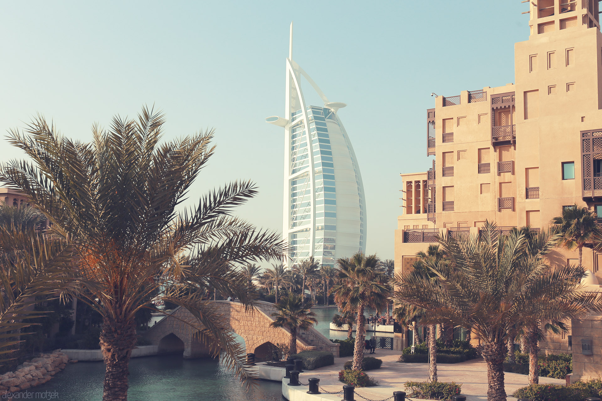 Foto von Palm trees and tranquil water frame the iconic Burj Al Arab in sunlit Dubai, blending tradition and modern luxury on the Arabian Gulf.
