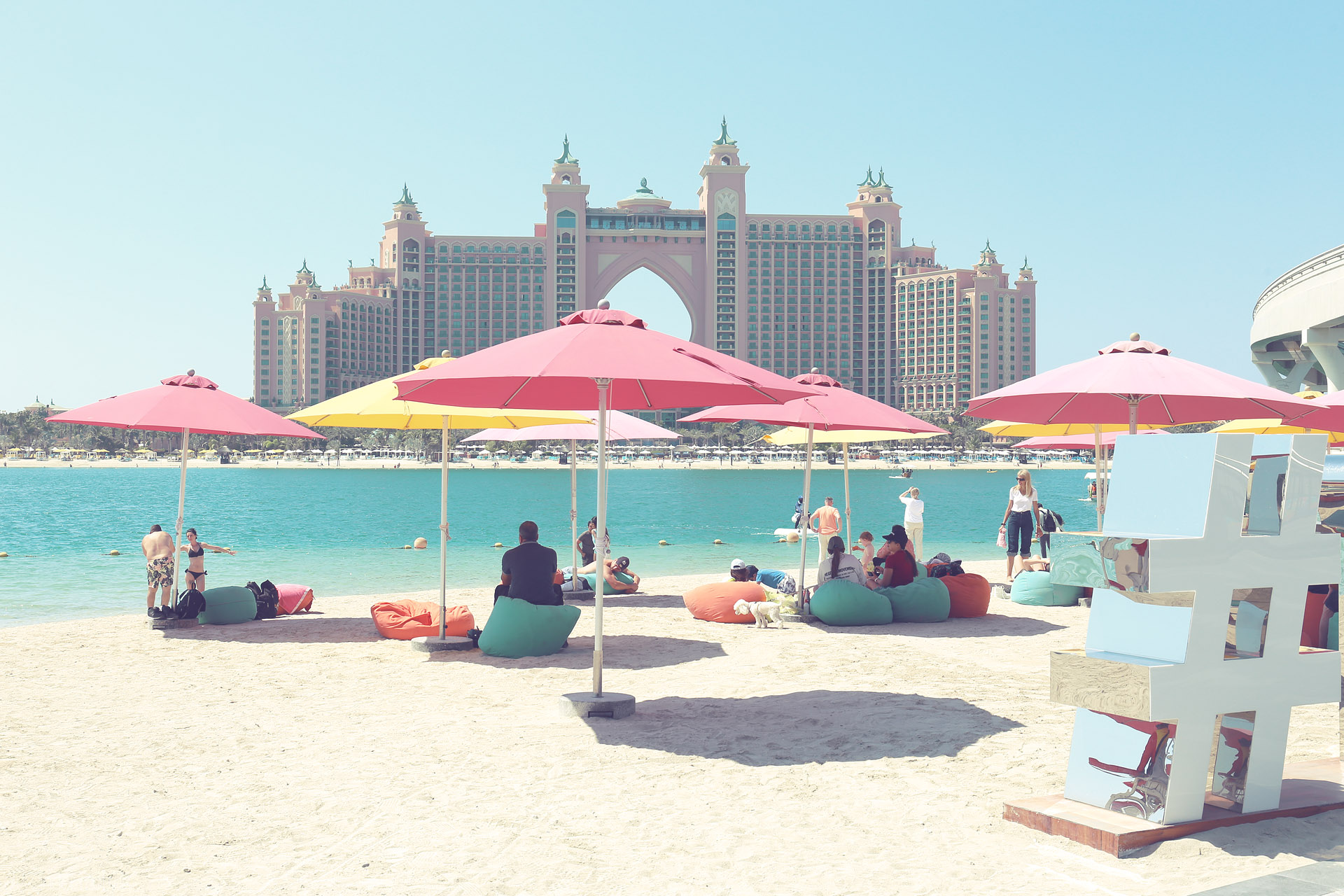 Foto von Pastel parasols on Palm Jumeirah beach gaze at Atlantis, under the Dubai sun—a modern majlis of leisure by turquoise Arabian waters.